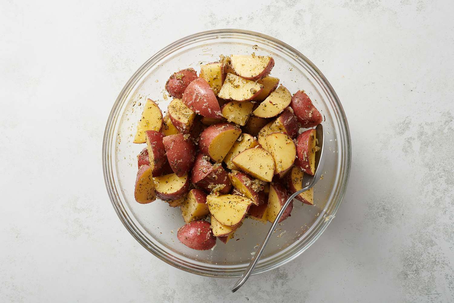 potatoes tossed with seasoning in a glass bowl