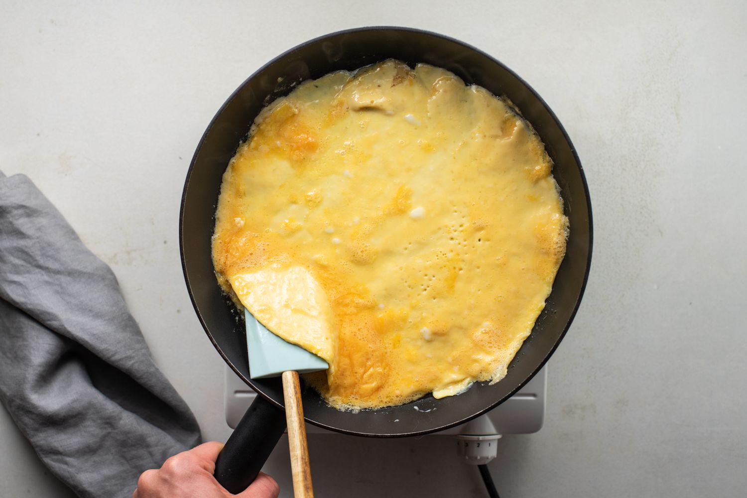 Edge of omelet in the frying pan being lifted with a spatula