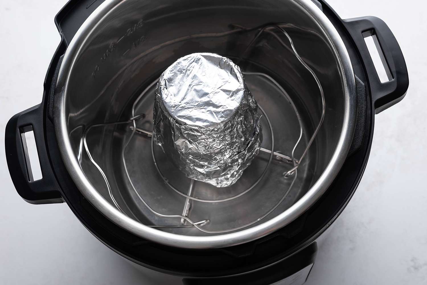Glass container with lemon mixture covered with aluminum foil in an instant pot