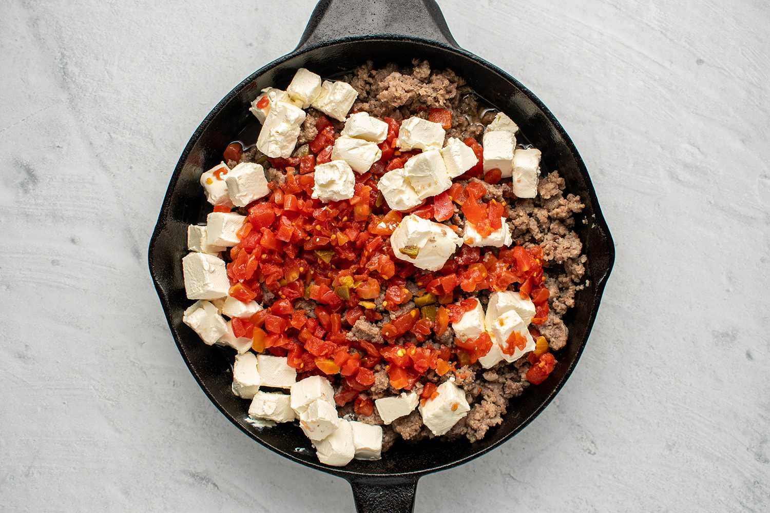Sausage with Rotel and cream cheese in a cast iron skillet 