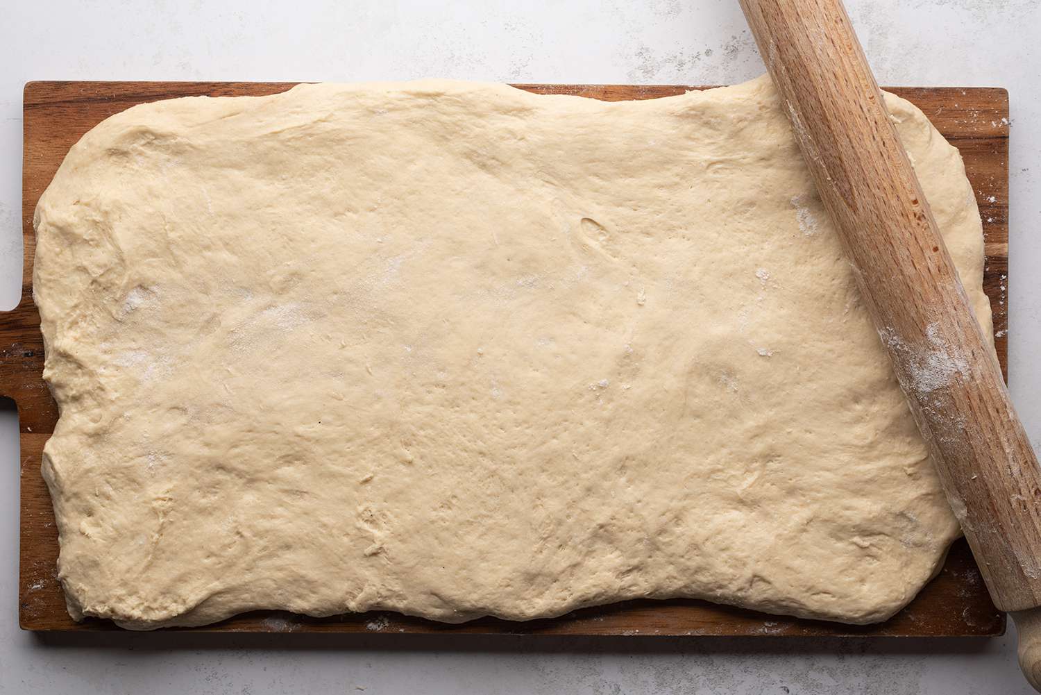 Dough rolled out with a rolling pin, on a wooden surface 