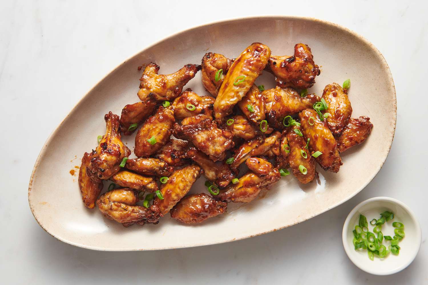 A large platter of air fryer honey-garlic chicken wings, garnished with sliced green onion
