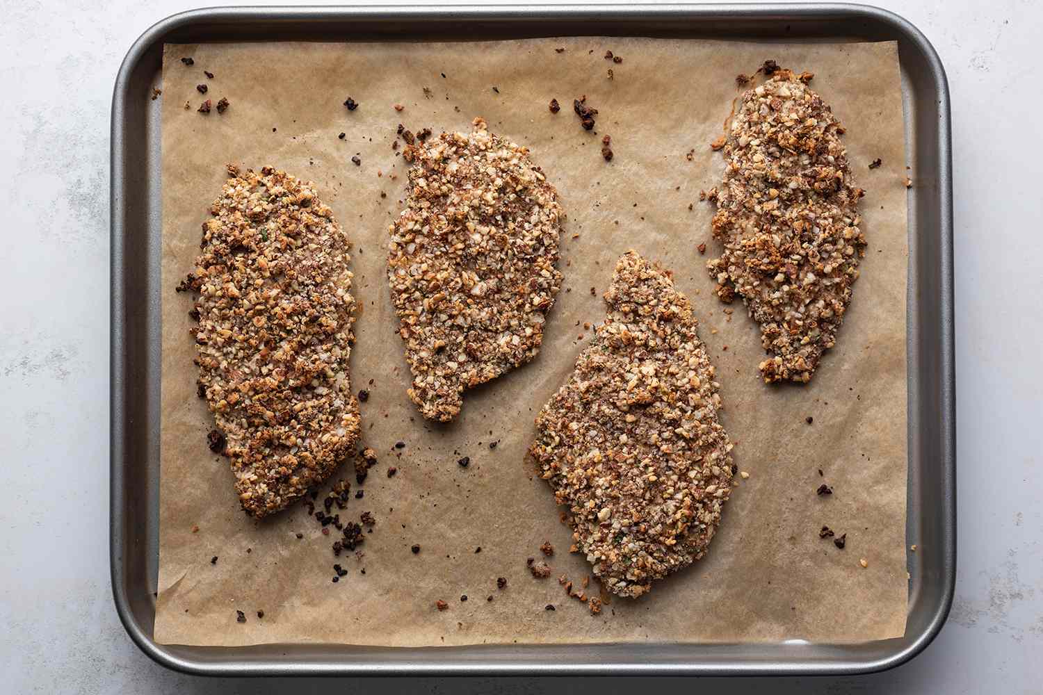 Baked Almond Crusted Chicken on a parchment paper lined baking sheet 