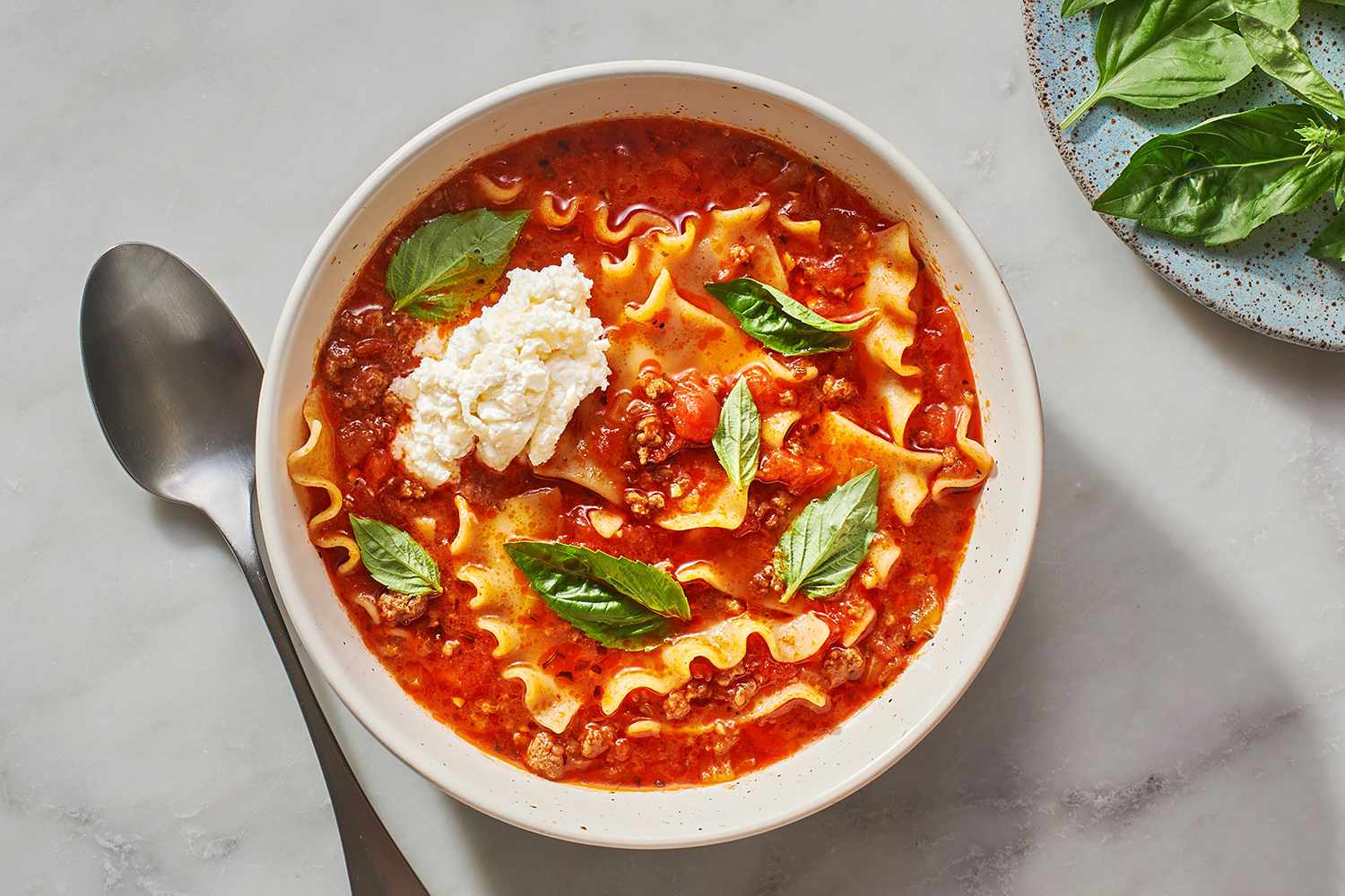 Bowl of lasagna soup topped with ricotta and basil