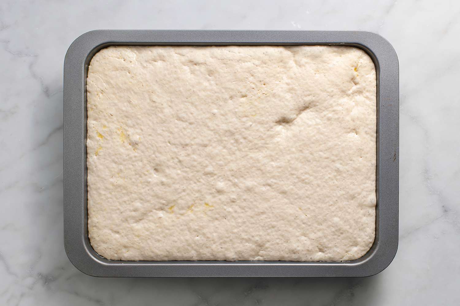 Focaccia dough rising in a baking pan