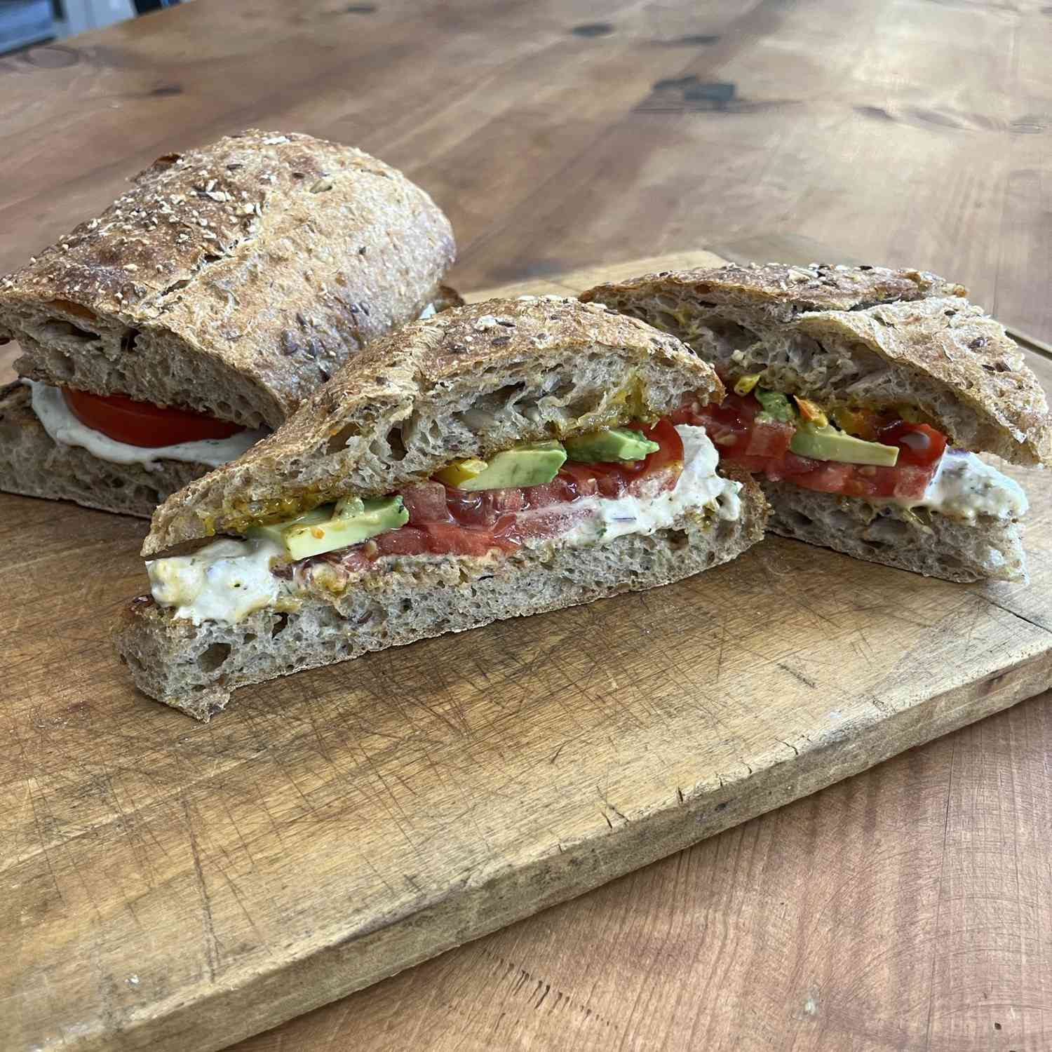 Whole grain bread topped with tuna salad, tomato, and avocado