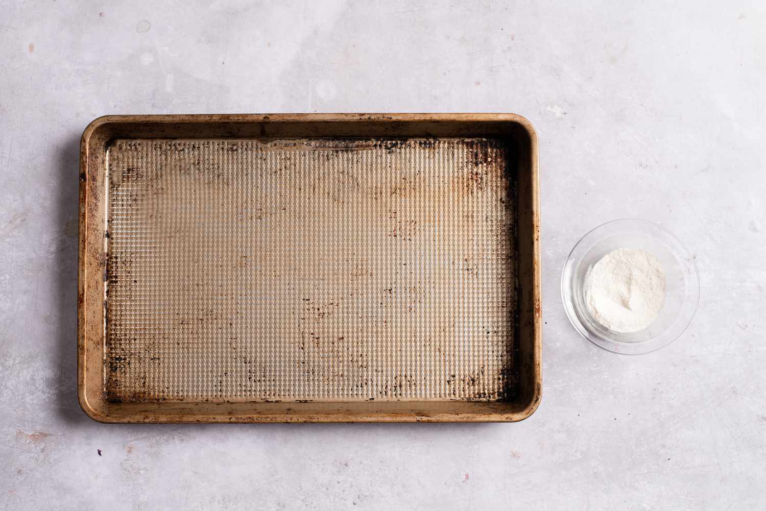 A small bowl of rice flour next to a baking sheet