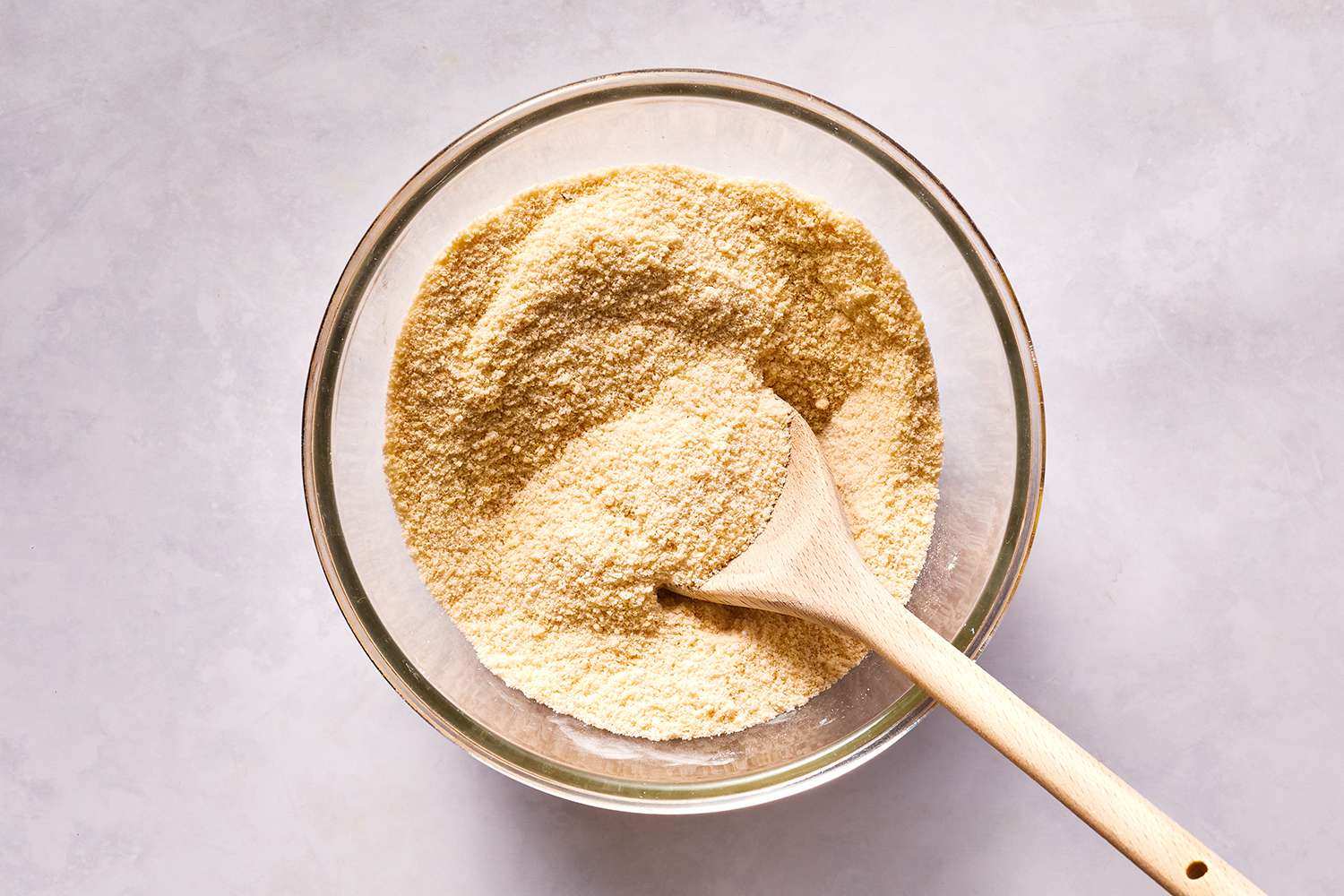 Flours, xanthan gum, baking powder, and salt in a bowl with a wooden spoon 