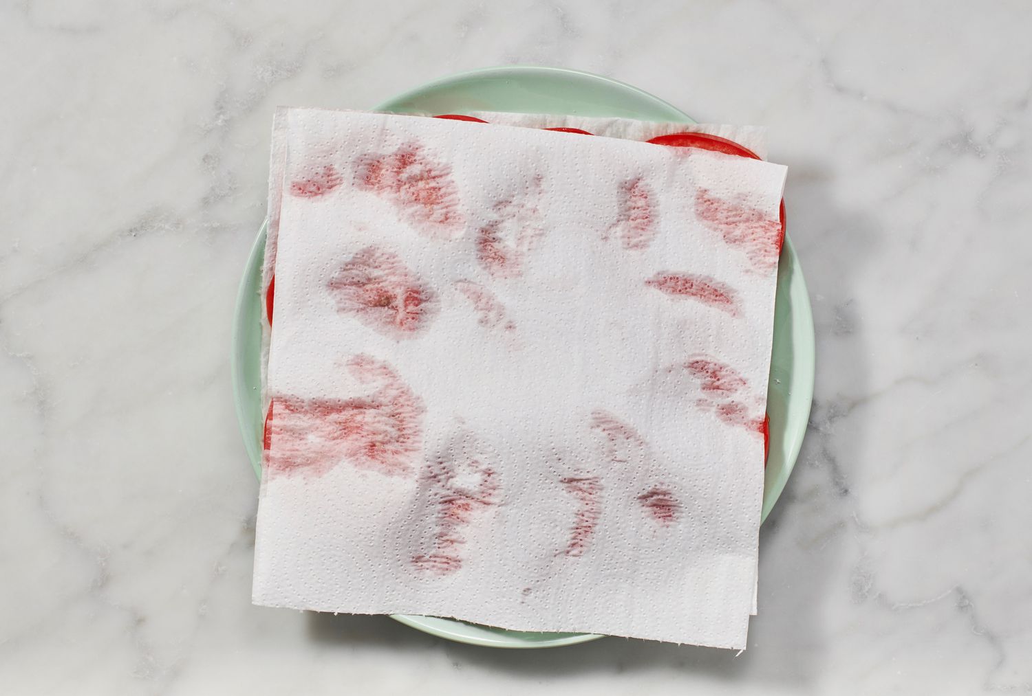 A plate of sliced tomatoes covered in paper towels