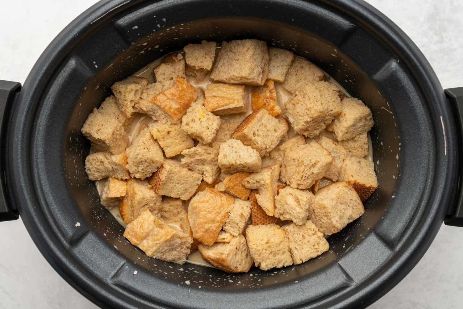 Egg and sugar mixture poured over cubed bread in slow cooker