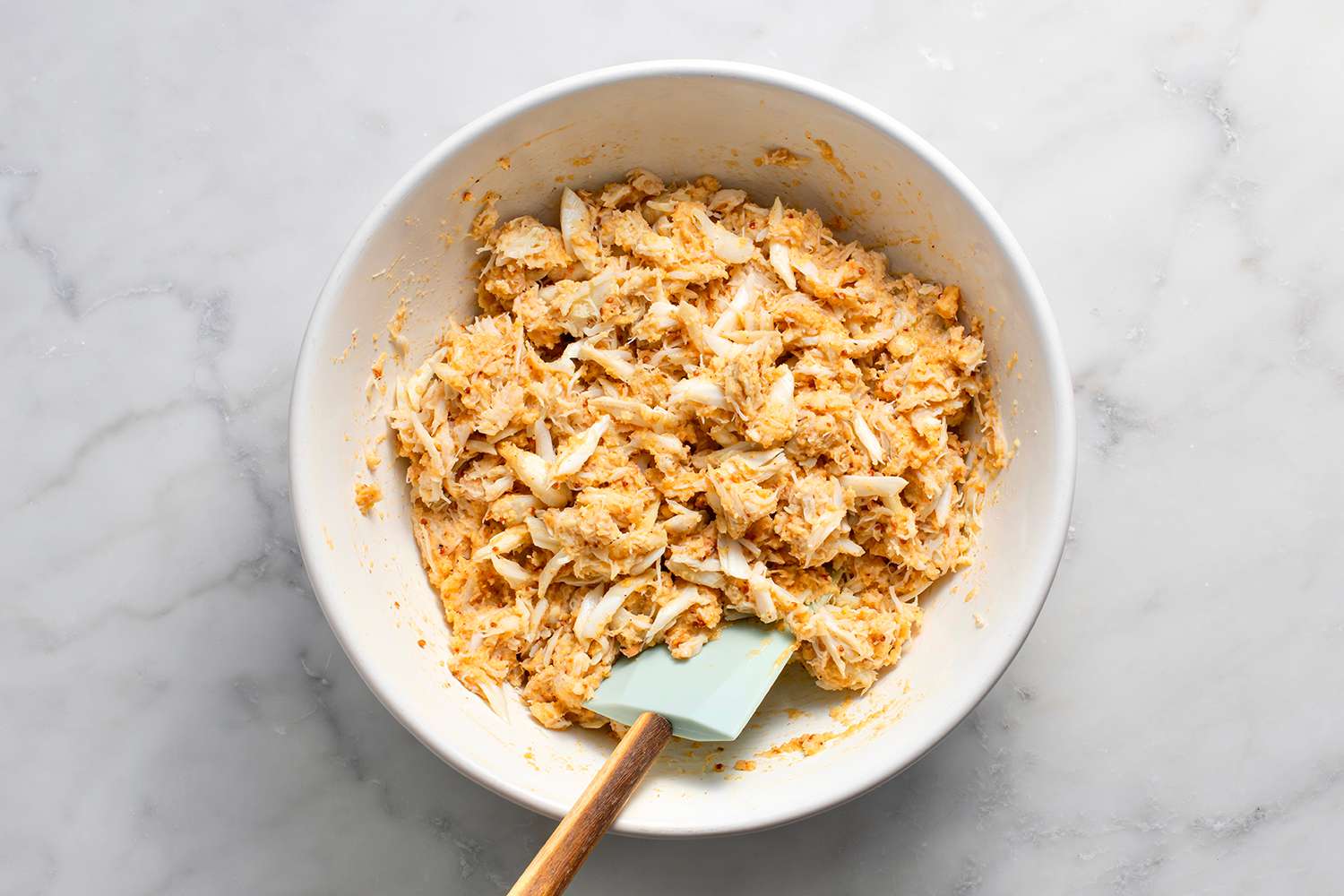 Crab, eggs, mayonnaise, Dijon and whole-grain mustards, salt, cayenne pepper, garlic powder, Old Bay seasoning, almond and coconut flours in a bowl with a spatula