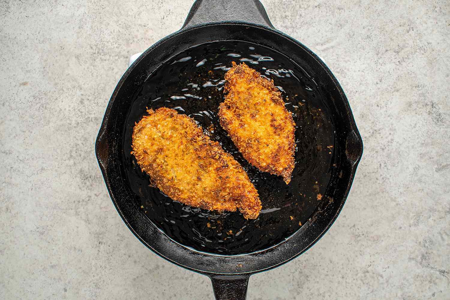 Breaded chicken frying in a cast iron pan 