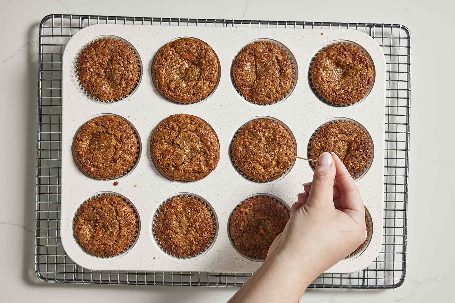 muffins from oven being tested with a toothpick