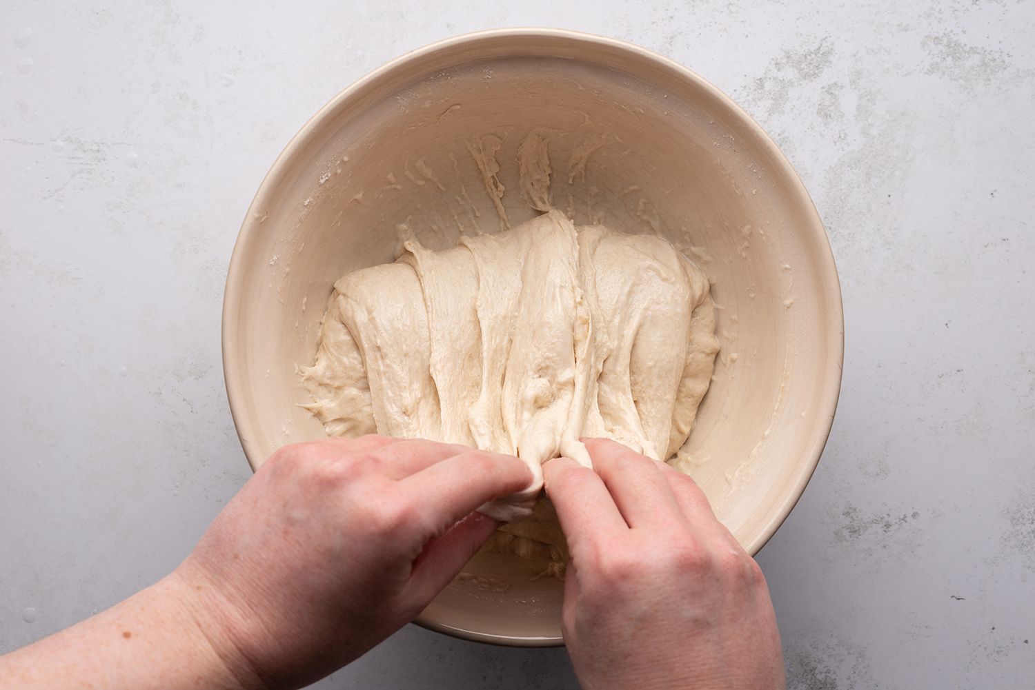 With wet hands, pick up one side of the dough, stretch it, and then fold it over onto the rest