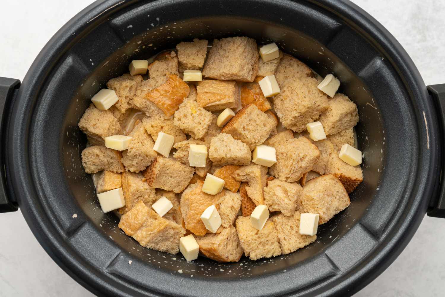 Cubed butter added to crockpot French toast