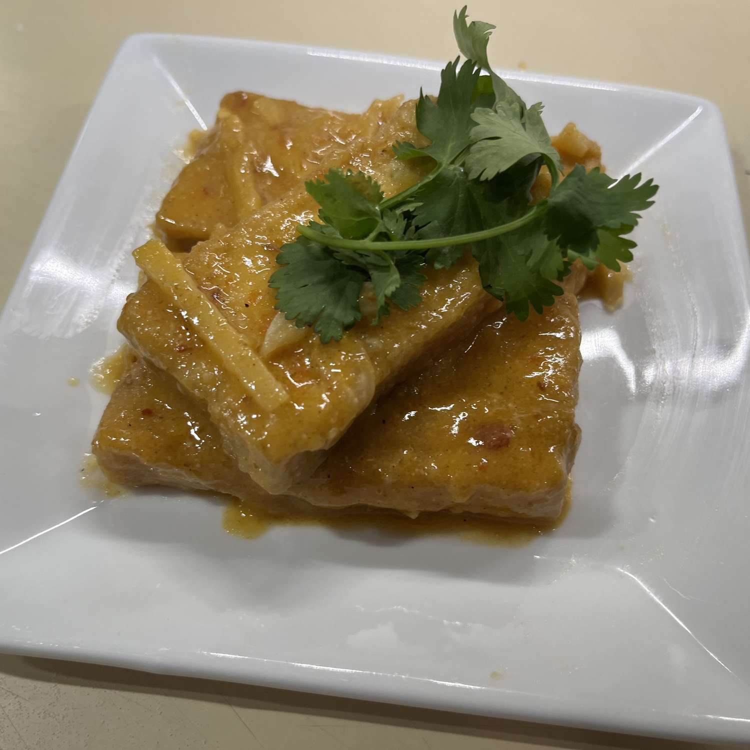 Three rectangles of glazed tofu topped with cilantro sprigs