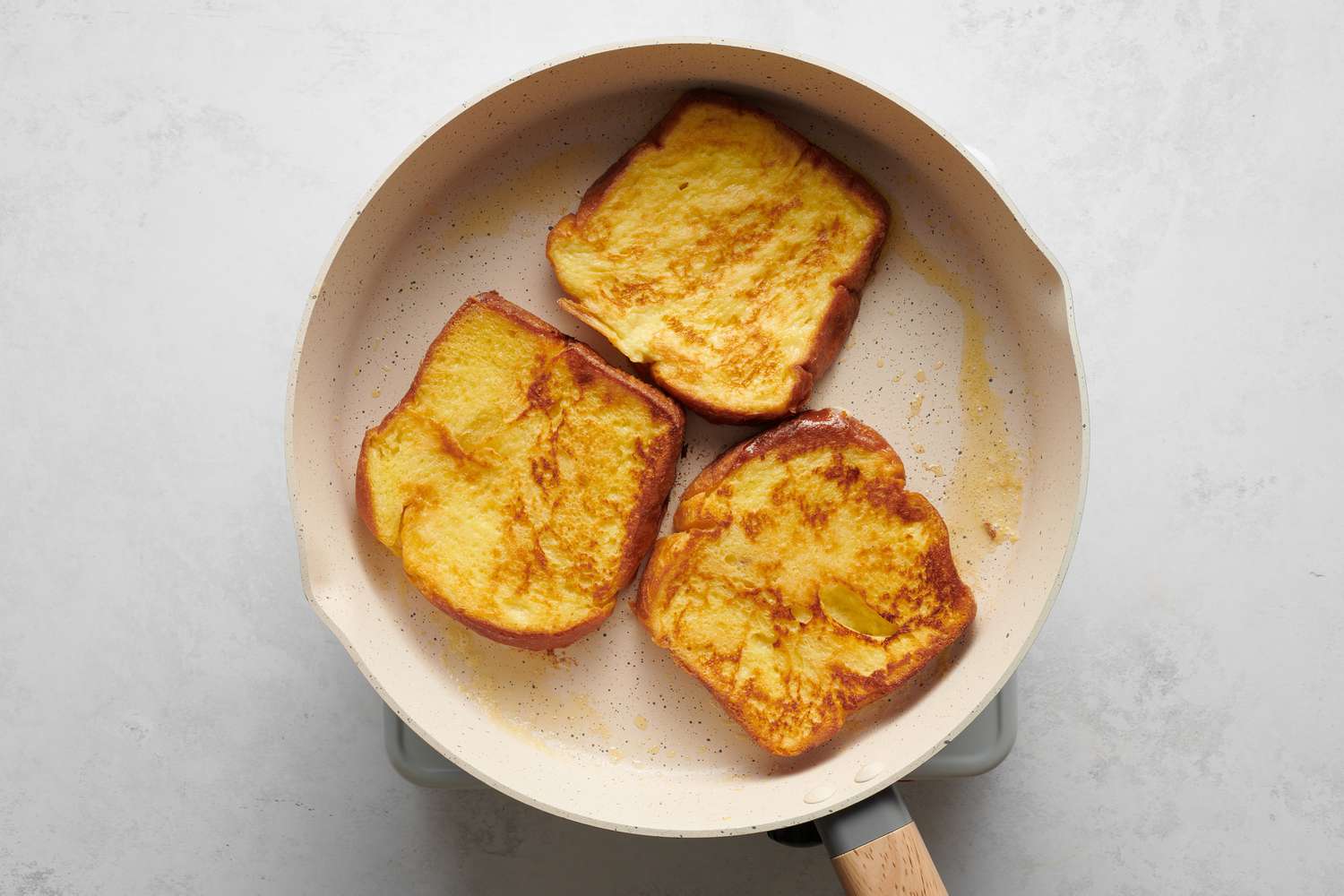 Three pieces of French toast cooking in a pan