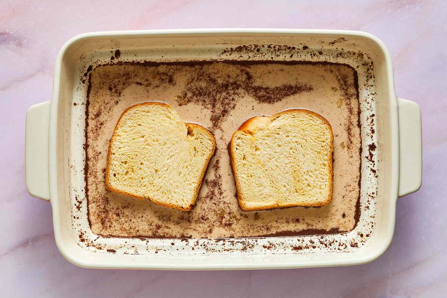 Two slices of bread soaking in custard