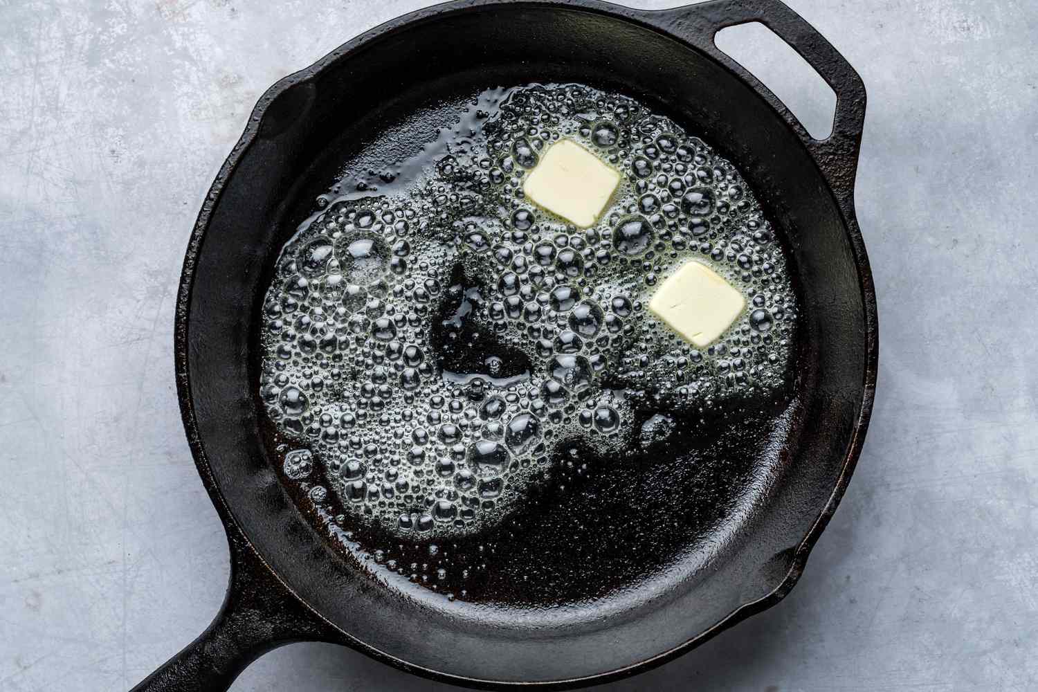 Two pieces of butter melting in a hot skillet