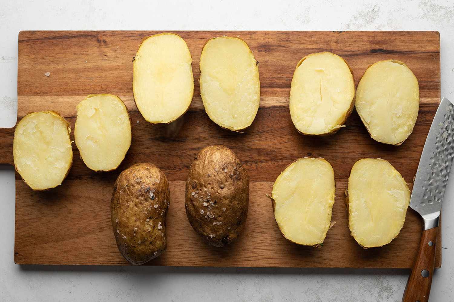 Potatoes sliced in half on a wooden cutting board 