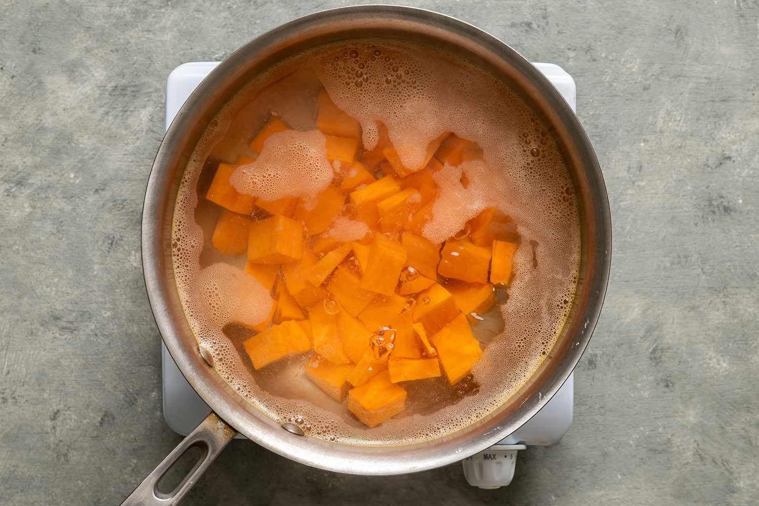 Diced sweet potatoes in a pot with water on a burner 