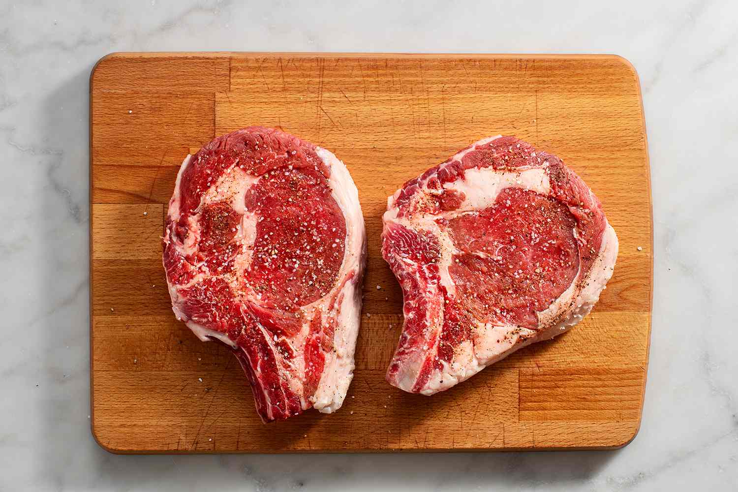 raw steaks sprinkled with salt and pepper