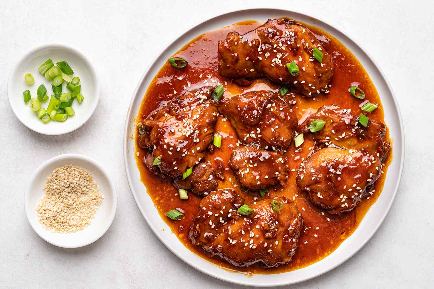 Instant Pot Honey Garlic Chicken on a platter, with a side of green onions and sesame seeds