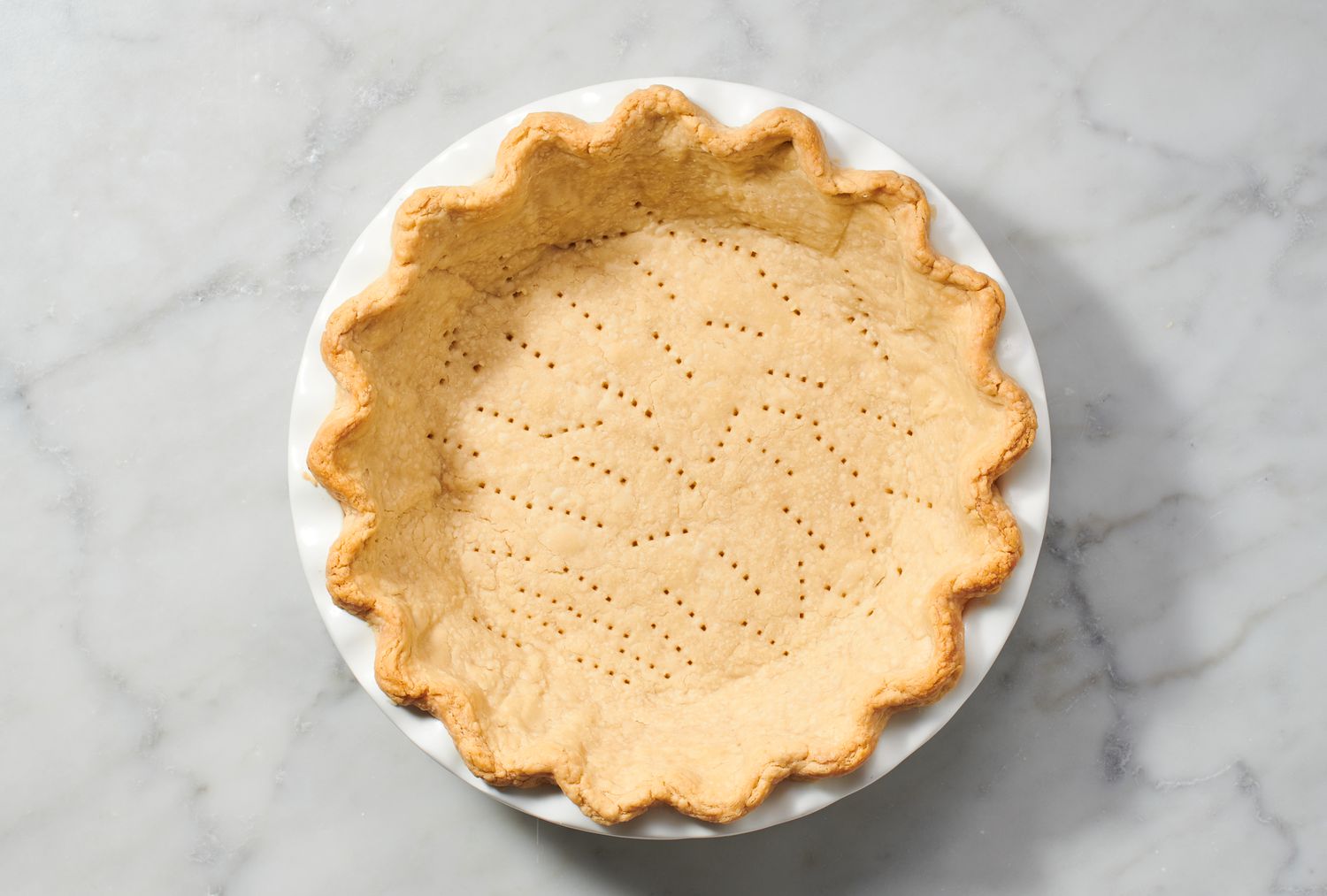 A par-baked pie crust with fork marks