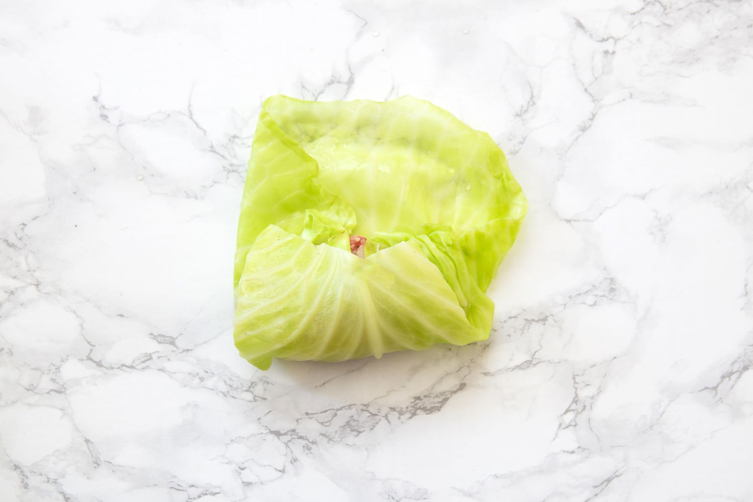 Cabbage leaf stuffed and rolled up on a white marble table