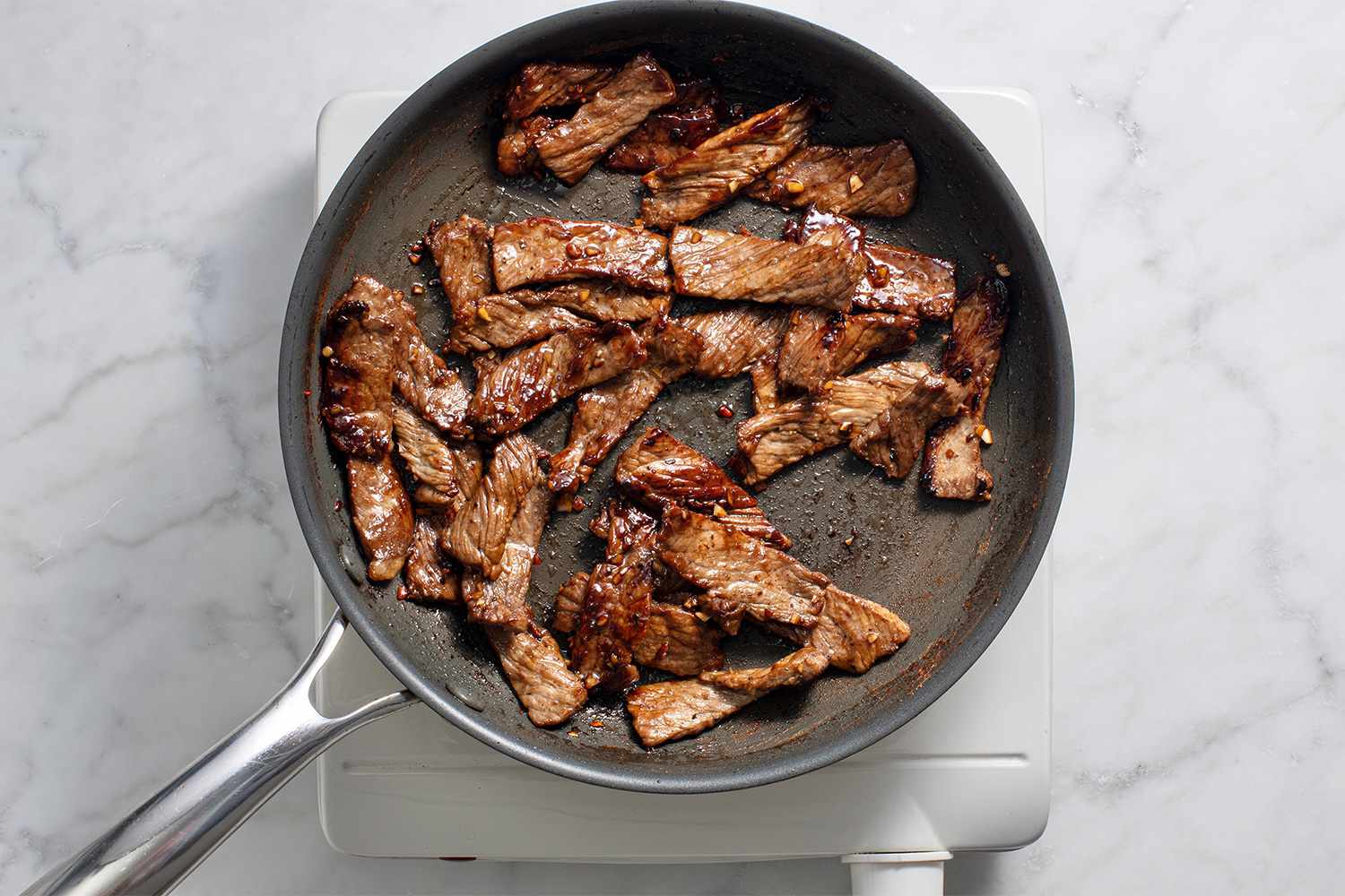 Meat cooking in a pan on a burner 