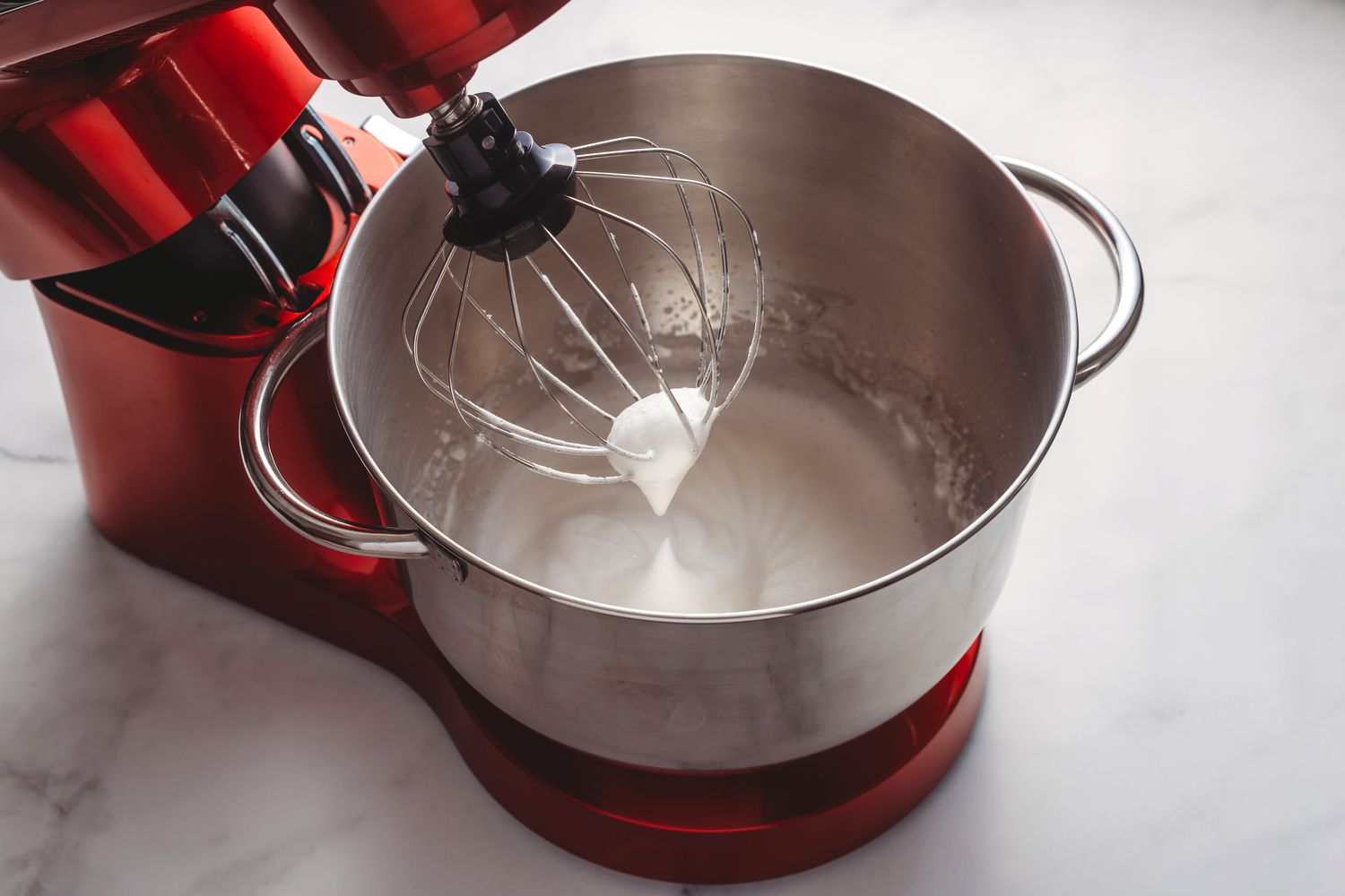 Egg whites being beaten stiff in a stand mixer with a wire whisk