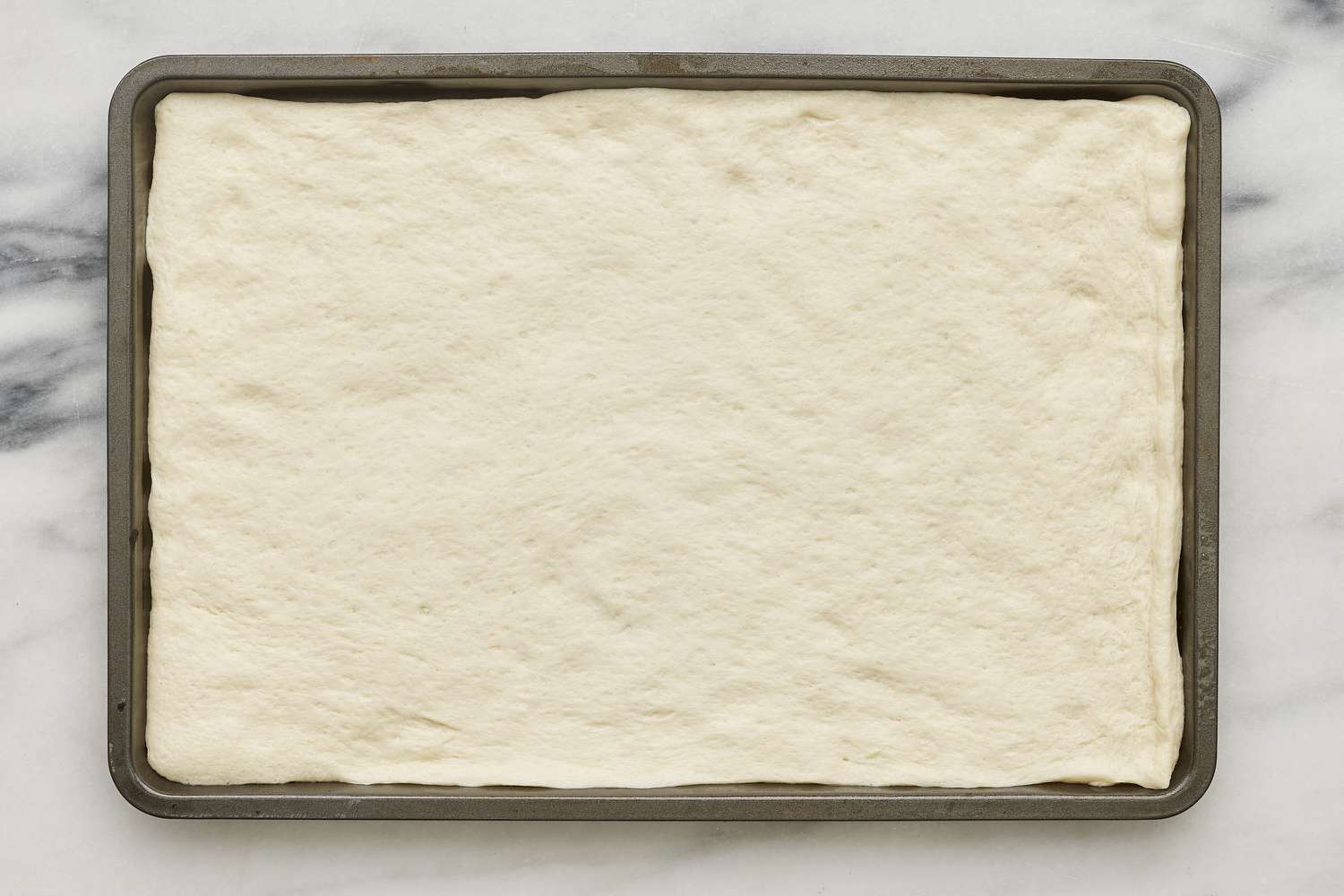 pizza dough unrolled onto baking sheet