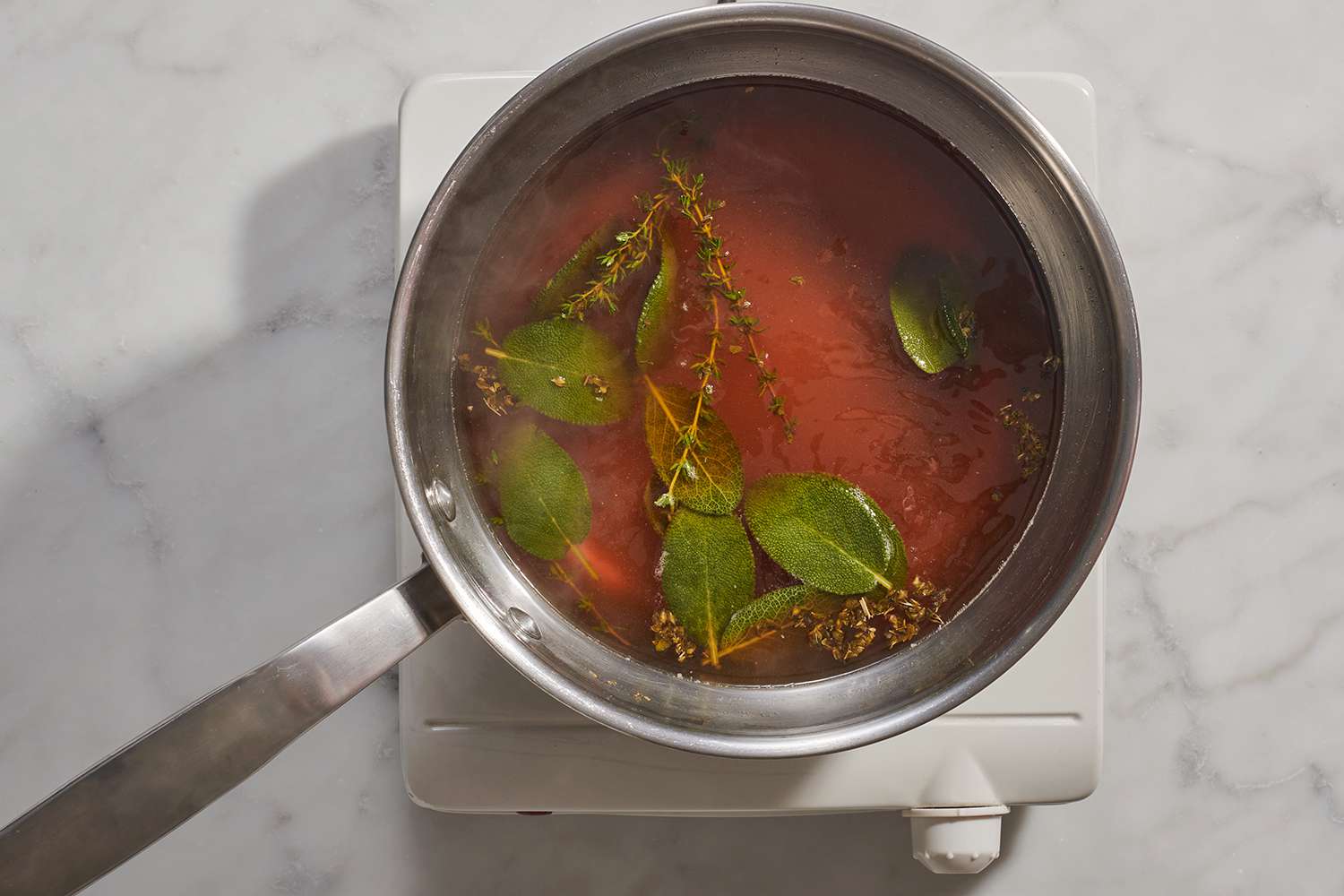 pork broth cooking in a saucepan with herbs