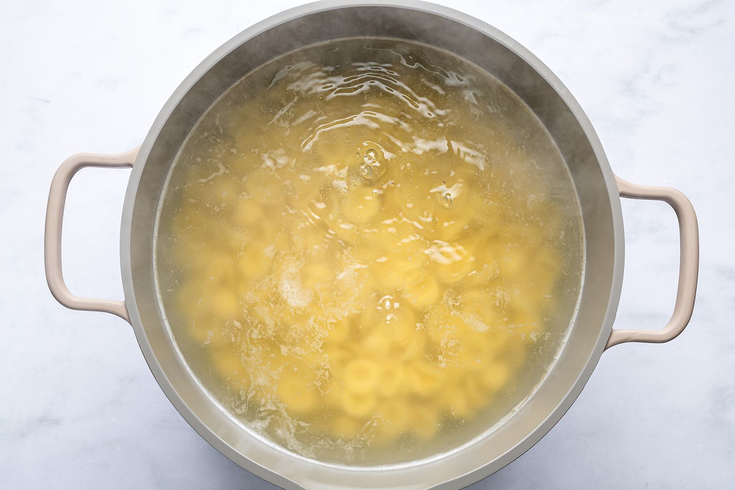 A pot of boiling water cooking orecchiette pasta