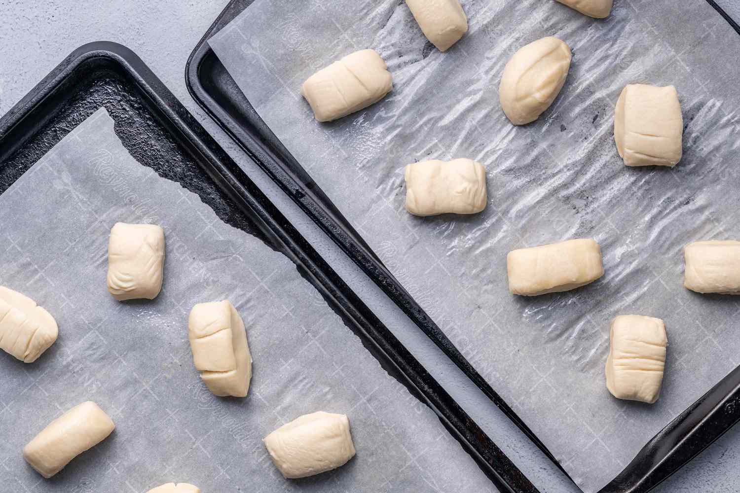 Pieces of boiled dough on parchment paper-lined baking sheets