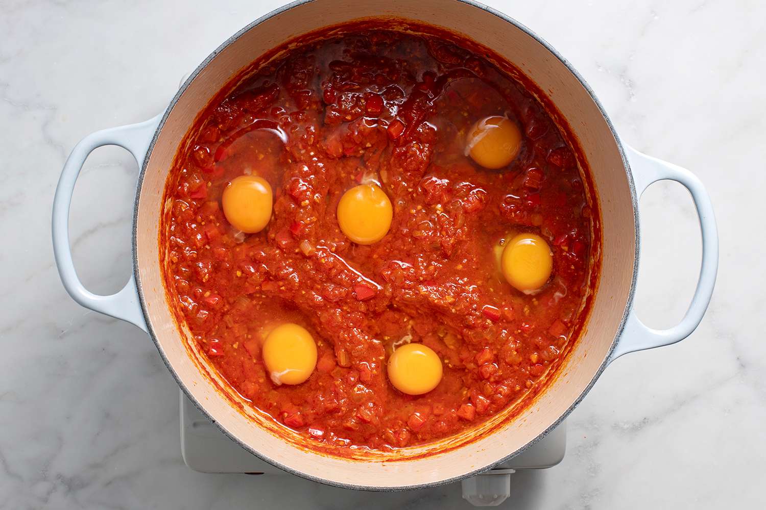 Eggs in the tomato sauce in a pot on a burner 