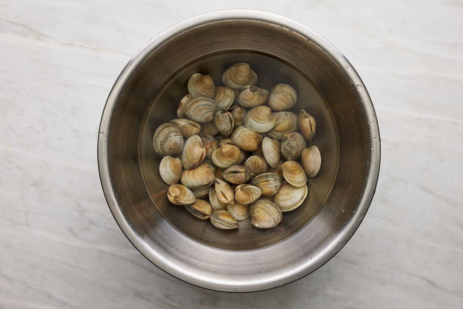 clams in bowl with salted water