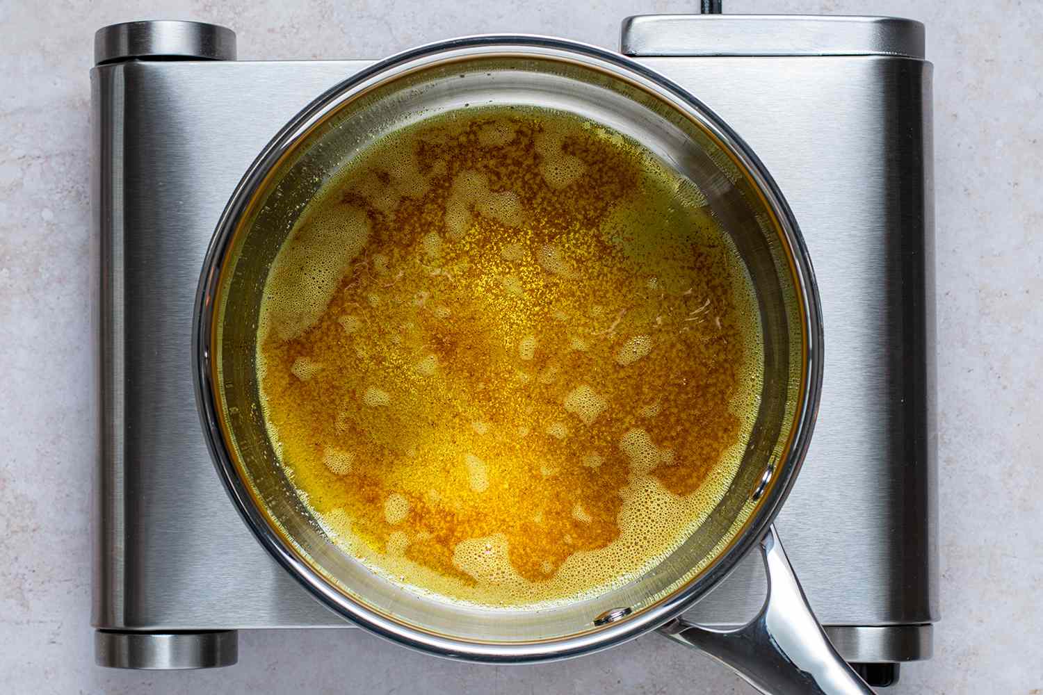 Oil, turmeric, curry powder, and rice in a saucepan on a burner 