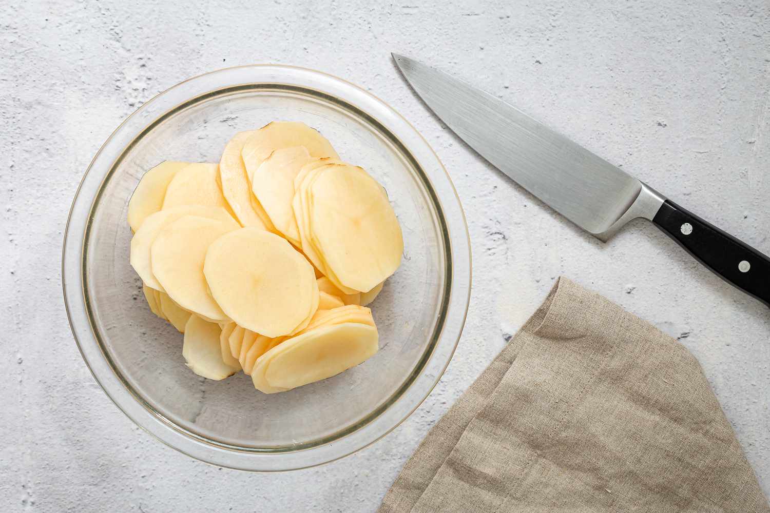 Peeled and thinly sliced potatoes in a bowl 