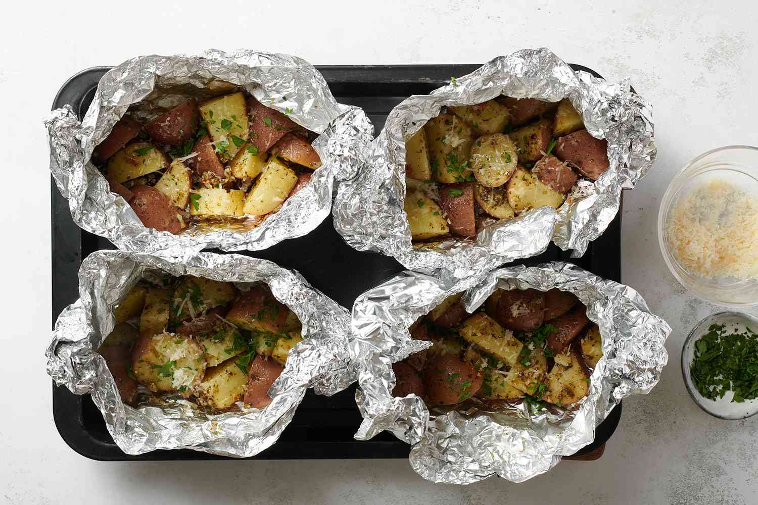 grilled parmesan potatoes in foil on a baking sheet