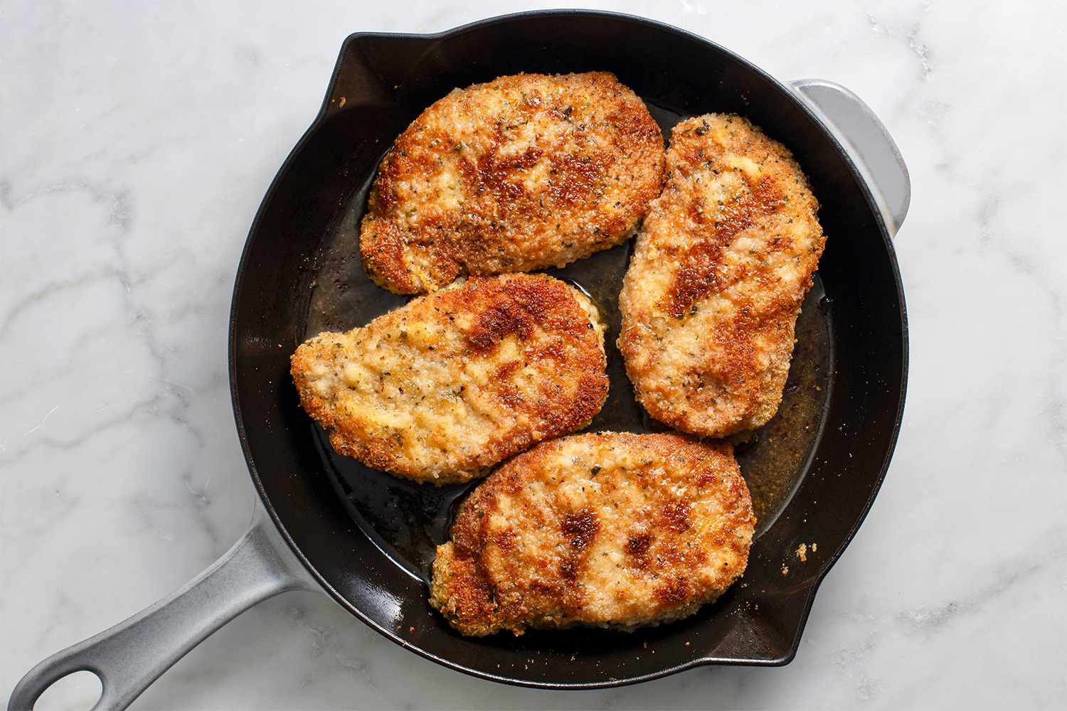 Breaded pork chops in a cast iron skillet 