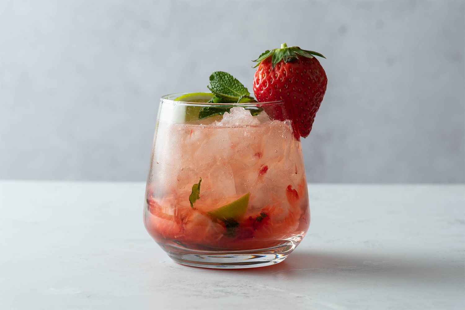 Strawberry Mojito in a glass, garnished with lime, mint and a strawberry 