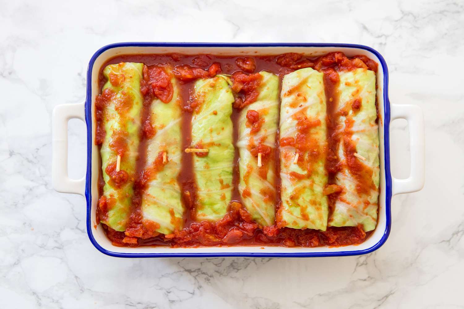 Cabbage rolls covered in tomato red sauce in a casserole dish