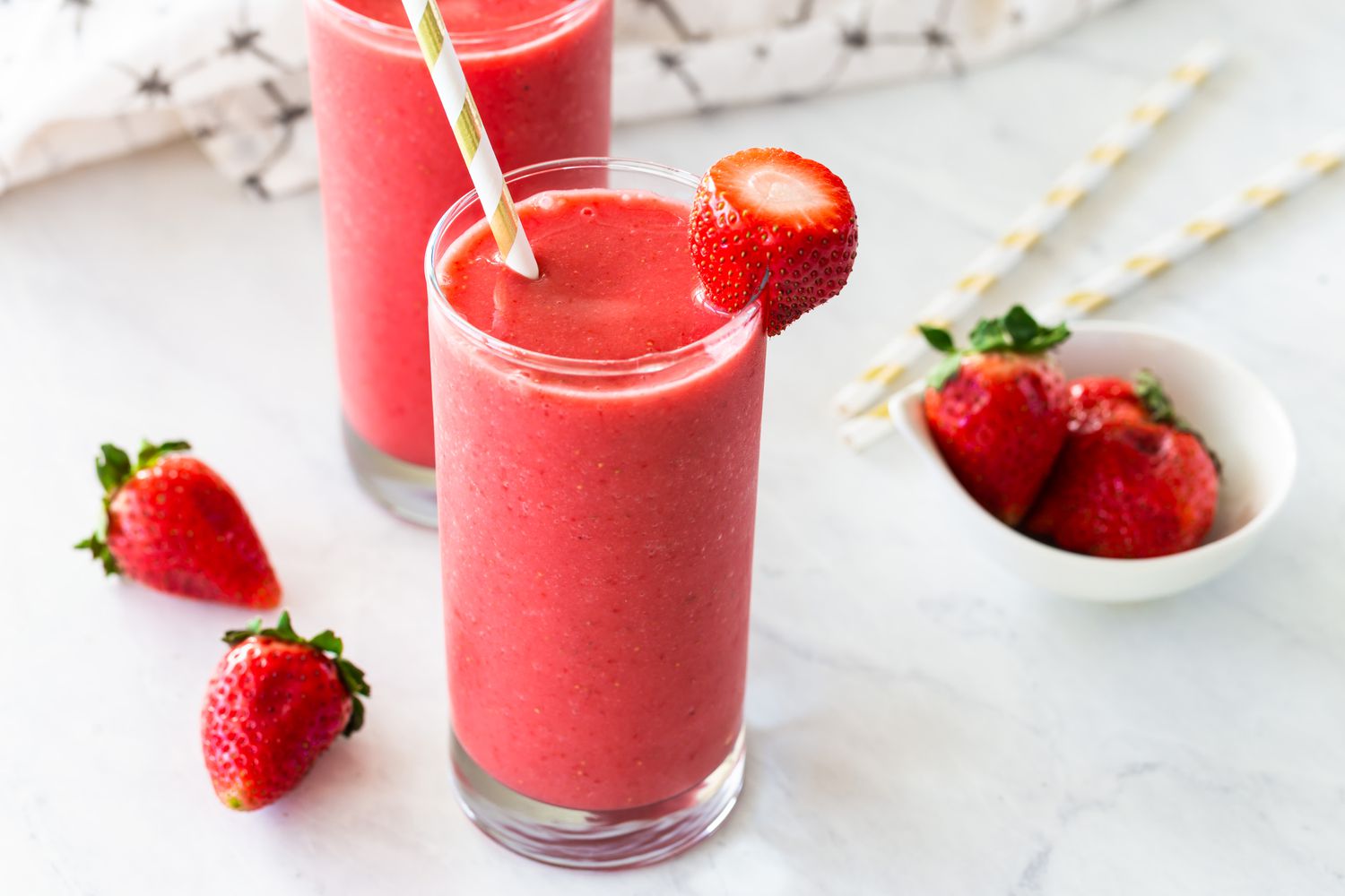 Two glasses of strawberry smoothies with strawberry garnish