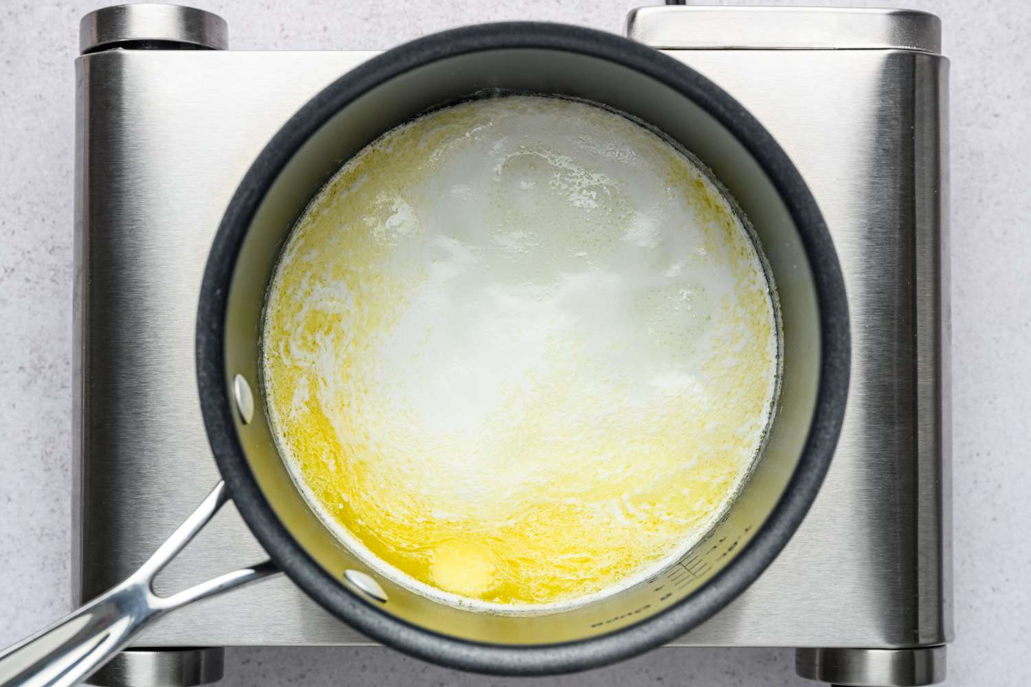 A pot of boiling milk, water, sugar, butter, and salt