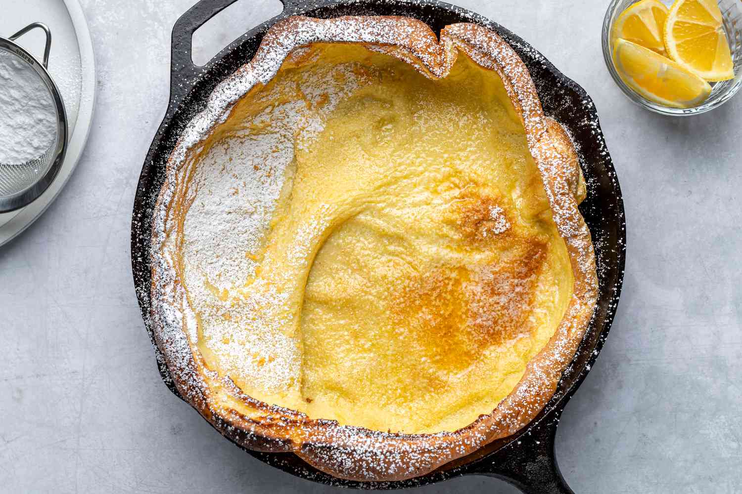 A Dutch baby topped with fresh lemon juice and powdered sugar