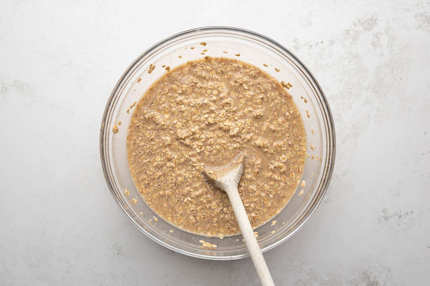 Oat mixture in a bowl with a wooden spoon 