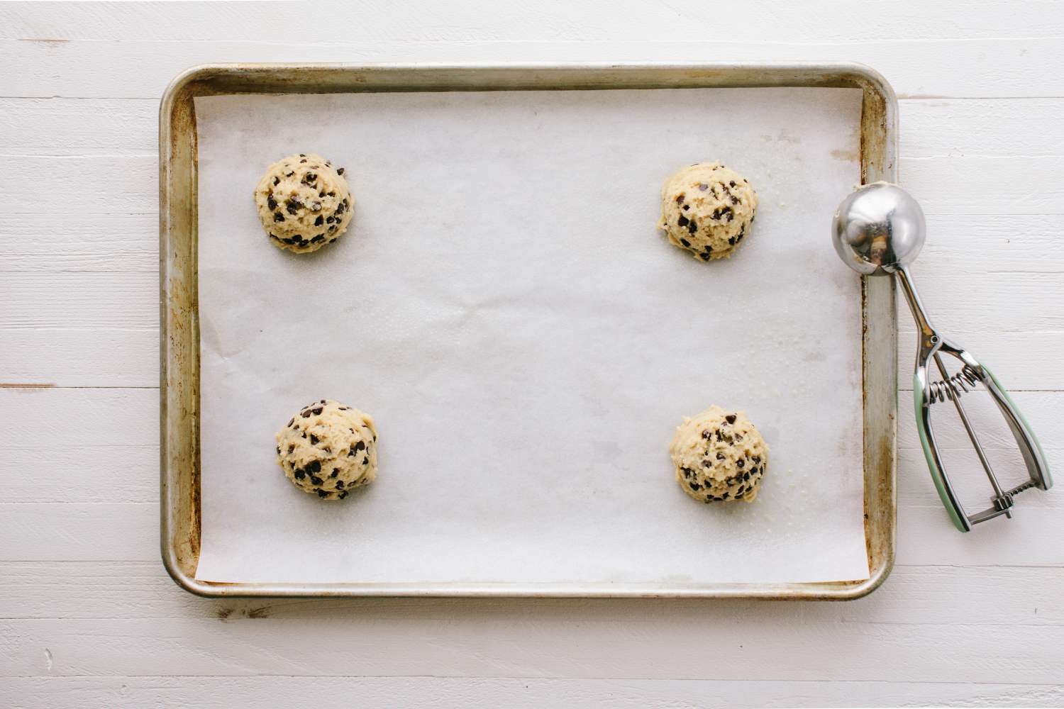 Cookie dough on prepared baking sheet with scoop on the side