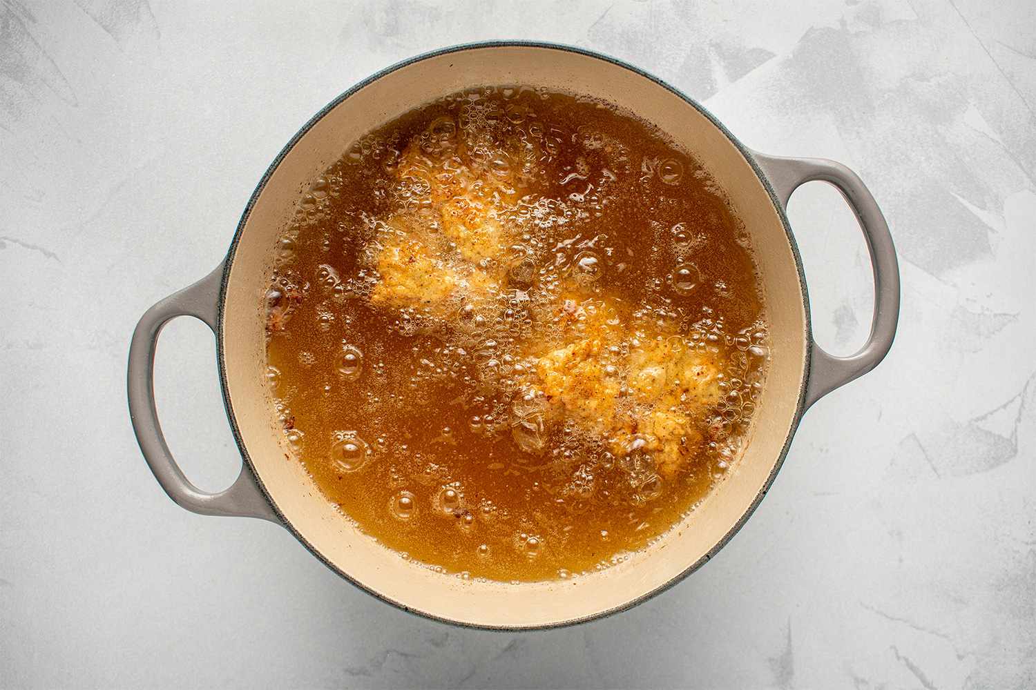 Breaded chicken frying in a pot with oil 