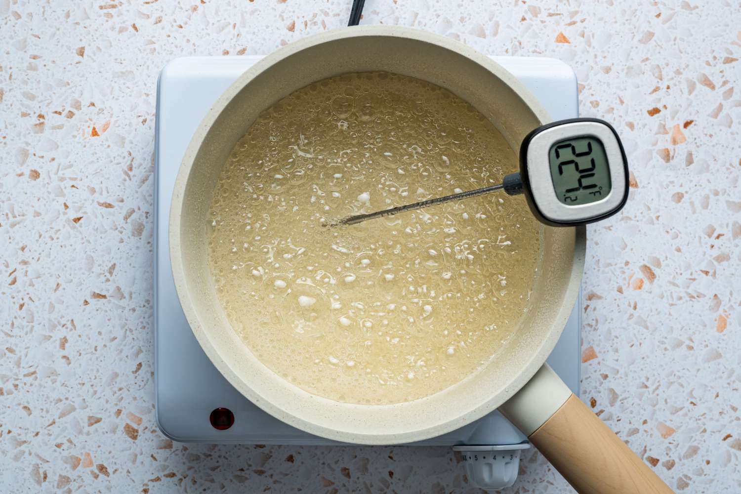 A pot of bubbling sugar syrup with a thermometer reading 224 degrees Fahrenheit 